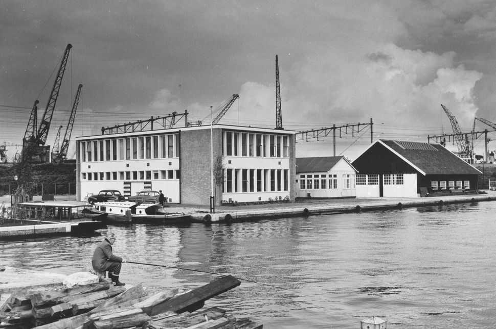 Foto van het nieuwe kantoor van de afdeling Haven- en Waterwerken kort na oplevering in september 1957. Rechts van het nieuwe kantoor staan een houten gebouwtje met een tekenzaal en de verplaatste Sluisdeurenloods. | Foto: beeldbank Stadsarchief Amsterdam (10009A004792).