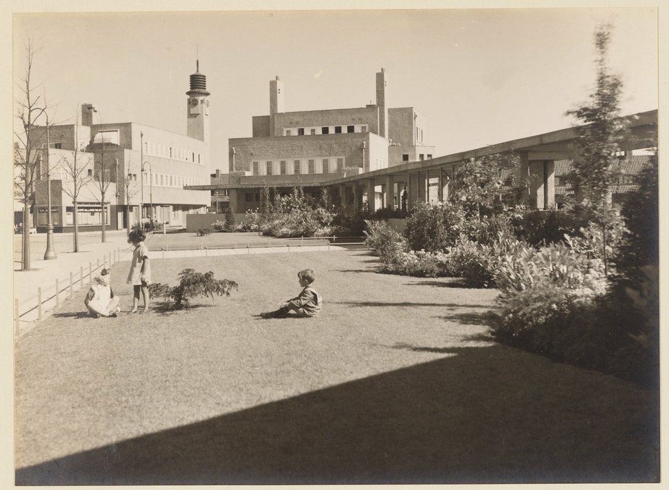 Rechts de gaanderij tussen Openbare Leeszaal en Verenigingsgebouw. Gezien naar Veeteeltstraat 106-116 en hoekhuis Brink 1 (links). Ontwerp van het hele complex: Dick Greiner. | Foto: Bernard Eilers (1928), beeldbank Stadsarchief Amsterdam (OSIM00008000782).